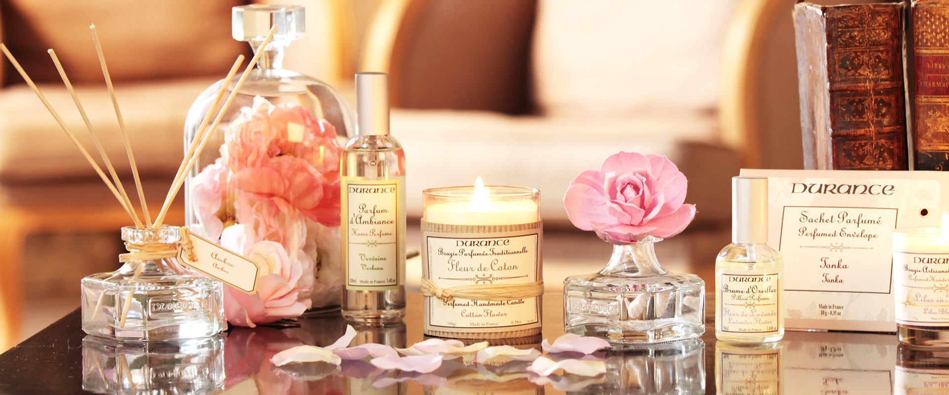 Durance home fragrance range, has flowers, candles and pillow spray. The table is warmly lit with petals over it. 